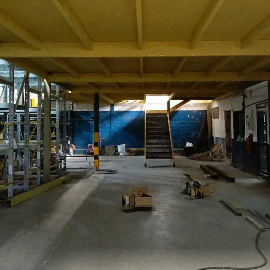 Interior de galpón con mezzanina y escalera amarilla