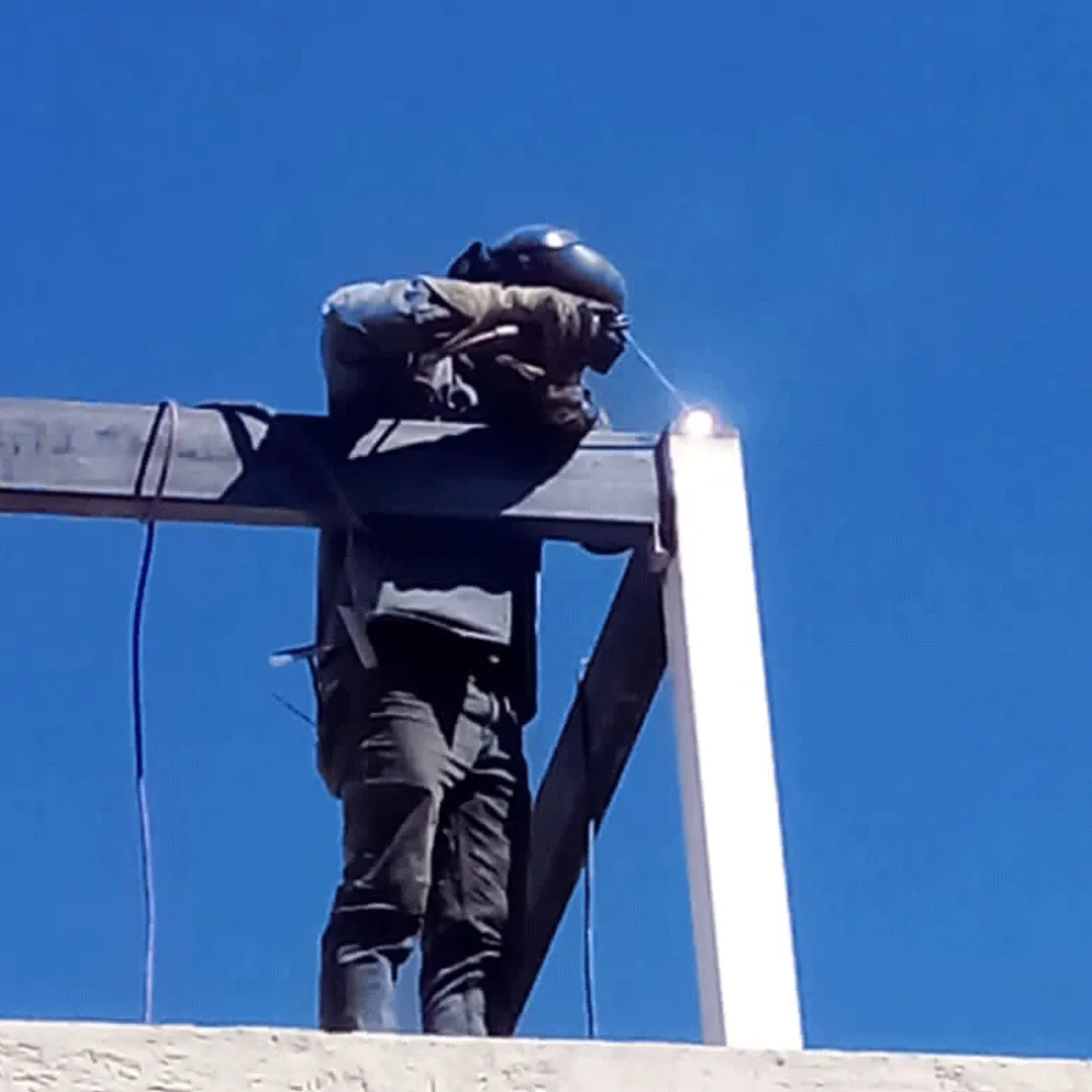 Soldador trabajando en gran altura con el arco de soldadura visible