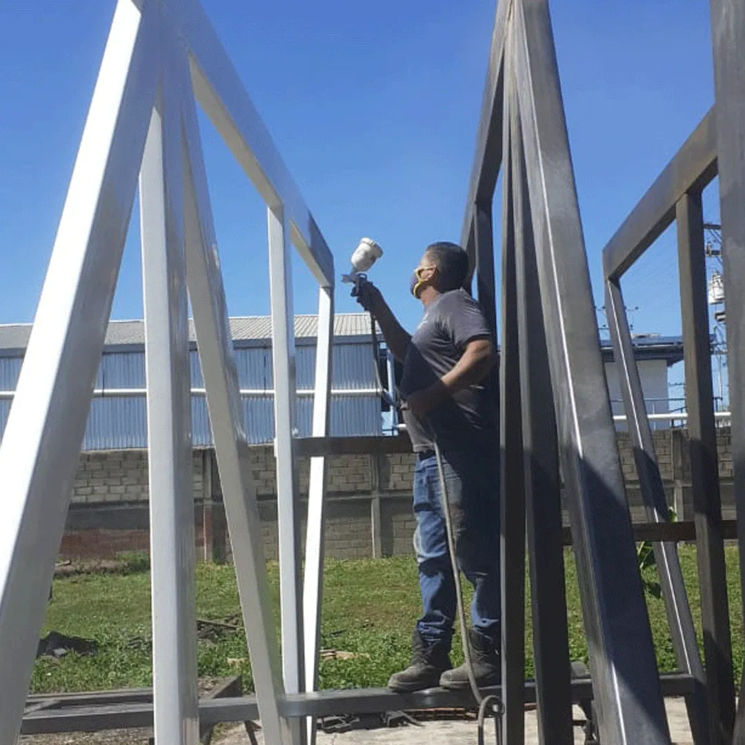 Trabajador aplicando recubrimiento a una estructura metálica con pistola